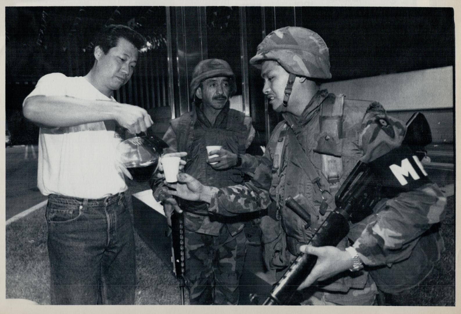 Coffee break: David Jang, an employee of a Los Angeles car dealership, serves coffee in the pre-dawn darkness today to two National Guardsmen guarding the business from looters