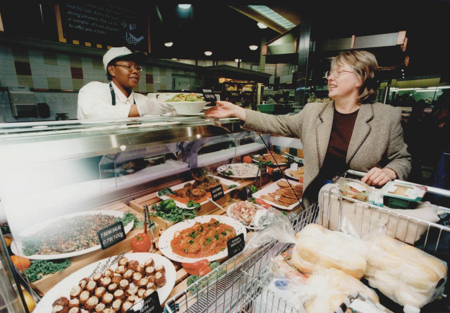 Ready to go: Social worker Madeleine Ellis, above, receives fresh prepared food from Andrea Barry at an IGA in Mississauga, which now has an extensive kitchen