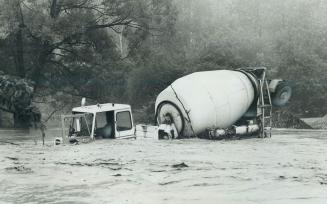 Rushing Floodwaters of Highland Creek in Scarborough all but submerge one of two concrete-mixer tucks that plunged in when entry ramp of bridge collap(...)