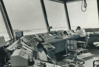 On Emergency standby Duty at Toronto International Airport tower, John Galashan, assistant air traffic controller sits alonein front of panel of instr(...)