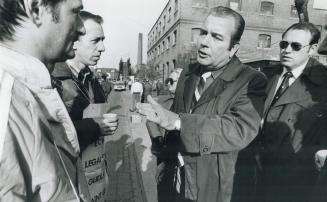 Keeping the peace: Sgt. Stan Gaylor, stripped tie, and Constable Gary Graham, sunglasses, talk to striking workers on the picket line at Glidden Paint(...)