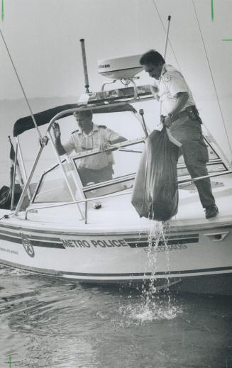 Scuttled service: Marine police officers John Winter, left, and George Dee recover a bag of mail about 100 metres (300 feet) off Cherry Beach yesterday