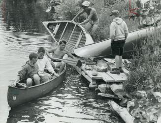 Ontario holiday: Boys' and girls' camps, Boys from a camp near Burks Falls make a portage at Magnetawan on their canoe trip in the Almaguin Highlands