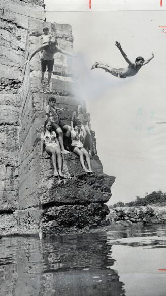 Flying from the heat, three boys dive together from the 25-foot-high Erindale Dam for a cooling dip in the five feet of water in the Credit River belo(...)