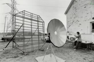 Outlaw of the airwaves: In Mississauga, David Brough picks up TV signals from satellites with dish, then relays it to the TV set via the device in his hand