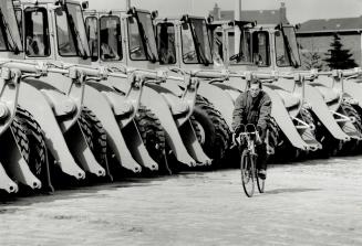 Crawling to a halt, A cyclist is dwarfed by a line of immobile equipment at Caterpiller Canada plant in Brampton on Sandalwood Dr. Built in 1983, it w(...)