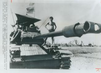 On guard at Xom Suoi, about 20 miles north of Saigon, a South Vietnamese soldier stands on his tank to survey the scene