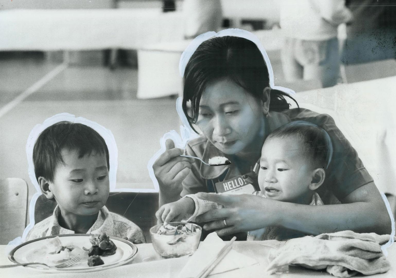 Le Banh, 10, Le Hoa, 13, and Le Binh, 4, watch television, Tran Thi Si helps her sons, Quach Suol, 5, and Quach Sen, 2, with their first Toronto meal