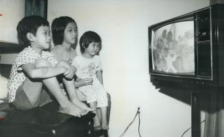 Le Banh, 10, Le Hoa, 13, and Le Binh, 4, watch television, Tran Thi Si helps her sons, Quach Suol, 5, and Quach Sen, 2, with their first Toronto meal