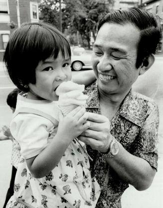 Tran Le Binh, 4, tries her first ice cream cone, held by her father, Lac Hoai