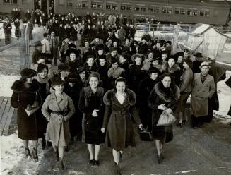Large group of smiling women coming off train 