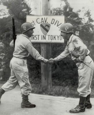 First G.I. to enter Tokyo, Pte. Paul E. Davis. 24, Fairland, Okla., left, gets a handshake from Maj.-Gen. W. C. Chase