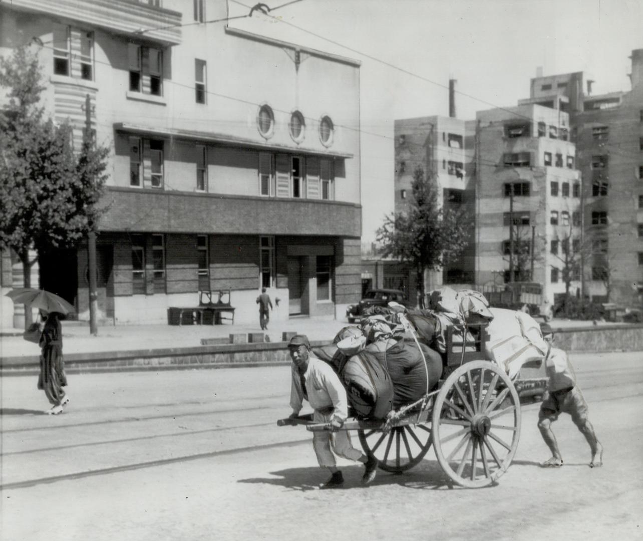 Back home go two Japanese with their possessions piled high on a handcart