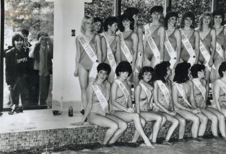 Sneak preview, Young boys peek through a window of the Triumph Sheraton hotel as Miss Canada contestants pose at poolside
