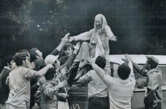 Students hail their new 'frosh queen', Their newly crowned Frosh Queen, blonde Joan Waskel, perched atop a bus, accepts the adulation of fellow studen(...)