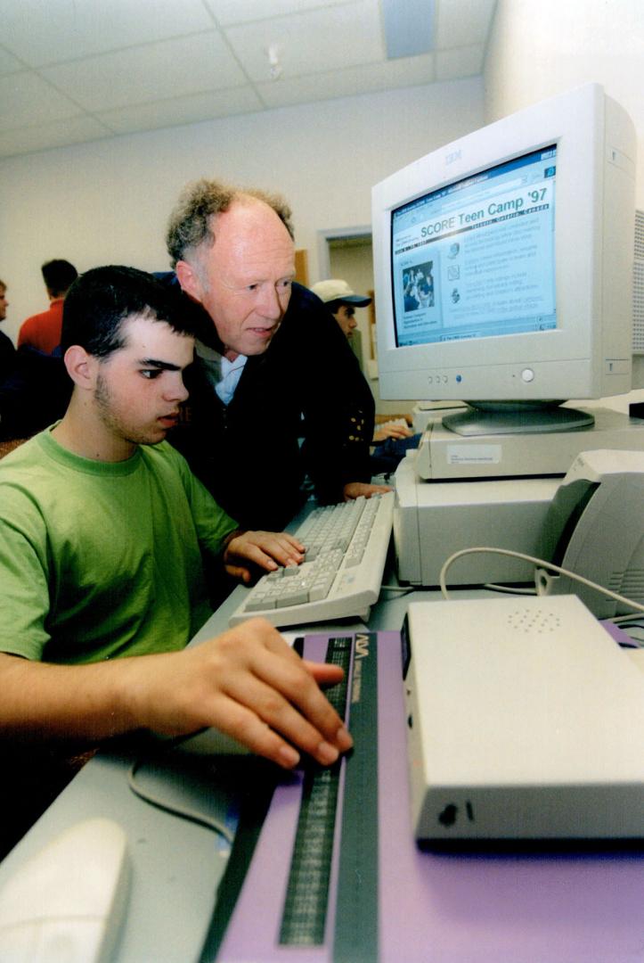 Canadian National Institute for the Blind staffer Don Murray peeks over the shoulder of Sebastien Massy, who is using a Braille device that lets him r(...)