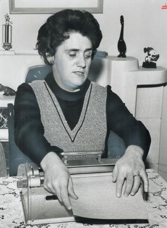 Blind for 29 years, Florence Carter reads what she has written on her Braille typewriter
