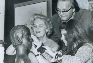 Sculptor-teacher Sidney Brown looks on as poet Mary Haws, left, and teenager Kathy Nessner, both blind, see a sculptured head with their sensitive fin(...)