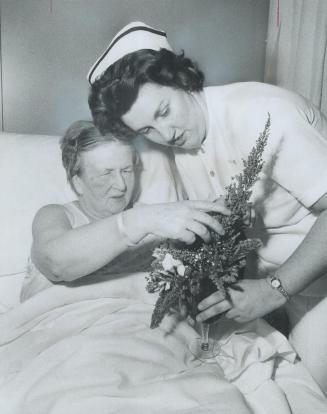 Blind for 50 years, Rose Crawford learns the color of flowers from a nosegay held by Doreen Wilson at Central Hospital