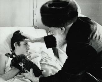 Rabbi Solomon Friedlander prays over sick Girl, He believes the Torah scroll in his left hand will help to cure her