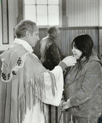 Peace offering: Rev. Jacques Johnson, wearing a robe of bearded deerskin as he celebrates Mass, gives communion to one of the members of his Cree and Metis congregation