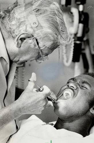 Open wide: Dr. Leo Sussman, who has been team dentist to the Toronto Argonauts for 15 years, goes to work on reserve quarterback Mike Williams. Sussman has been attending Argo games since 1945