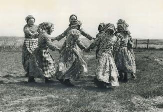 Hutterite girls in everyday dress dance in a circle during school recess in a Saskatchewan settlement