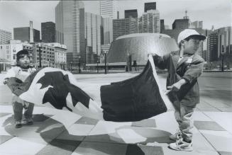 Edward Jon-Soo, 2, left, and his brother Timothy Sung-Soo, 3, wrestle with the wind to unfurl a Canadian flag at Metro Hall. They were among 400 newco(...)