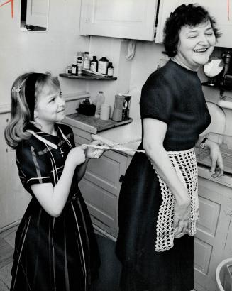 Getting lunch is no problem for Mrs. Daniel Ingrouville but tying on the apron is so daughter Cynthia, 9, gives her a hand. Mrs. Ingrouville has rheum(...)
