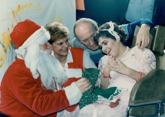Sharon Meehan, 21, right, is delighted as Santa Claus (her brother Shawn) shows her gifts while her parents Larry and Georgette watch