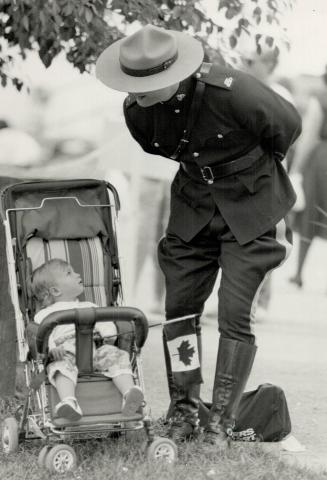 Image shows RCMP Officer looking at the toddler in the stroller with a Canadian flag.