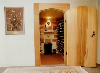 The solid cedar door, above, and an Acutemp (centred on the quarry tile floor at the back wall) keep the cellar at a constant 13C (55 F)