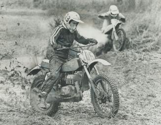 Charging over the Etobicoke course, leaving a rooster-tail of mud, is 16-year-old Gordon Davey on his 125cc machine