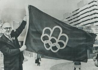 Montreal Mayor Jean Drapeau, in Munich yesterday, waves a specially-made flag with the emblem of the 1976 Olympic Games, to which Canada will be host.(...)