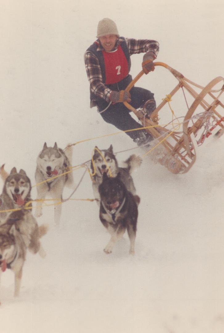 With their sled almost airborne, hard-driving huskies haul Doug McNeil of Guelph to victory in the 9