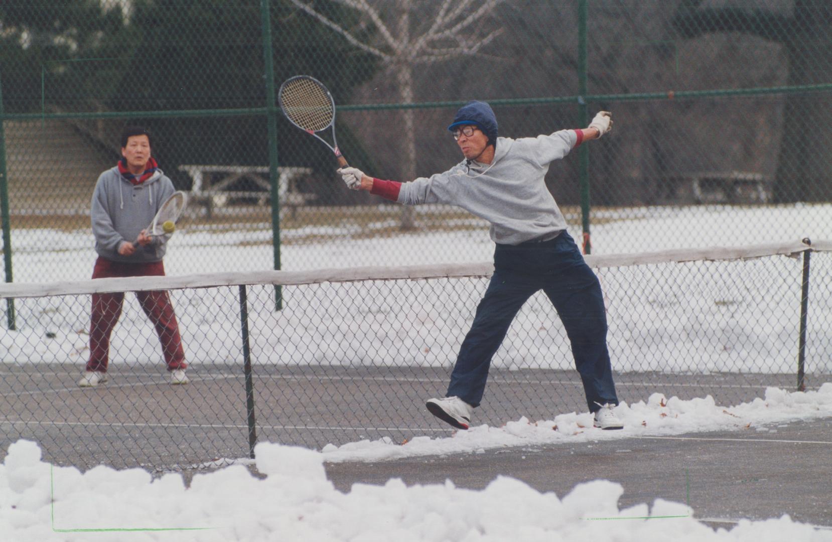 Diehard tennis players Kim in Bok (foreground) and Kiwoong Bae don't let a little snow keep them from the court cleared all winter