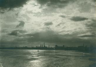 Image shows a lake view under the dark clouds with the Harbour buildings in the far background.