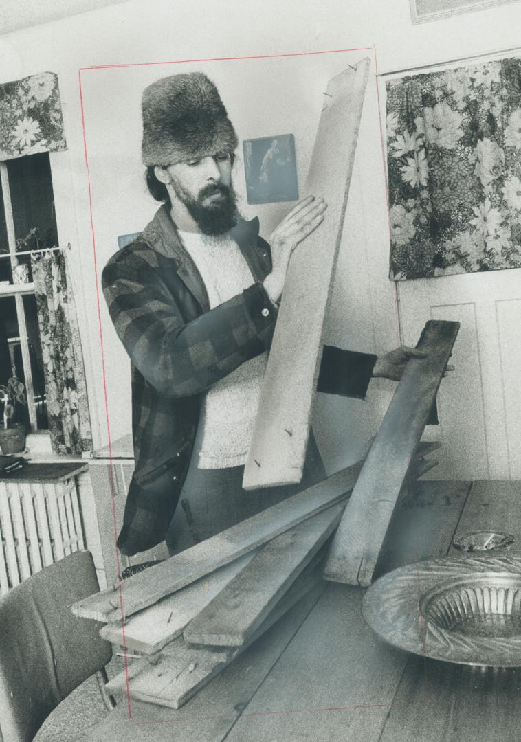 Don Riggan sorts packing-crate lumber to convert it into furniture