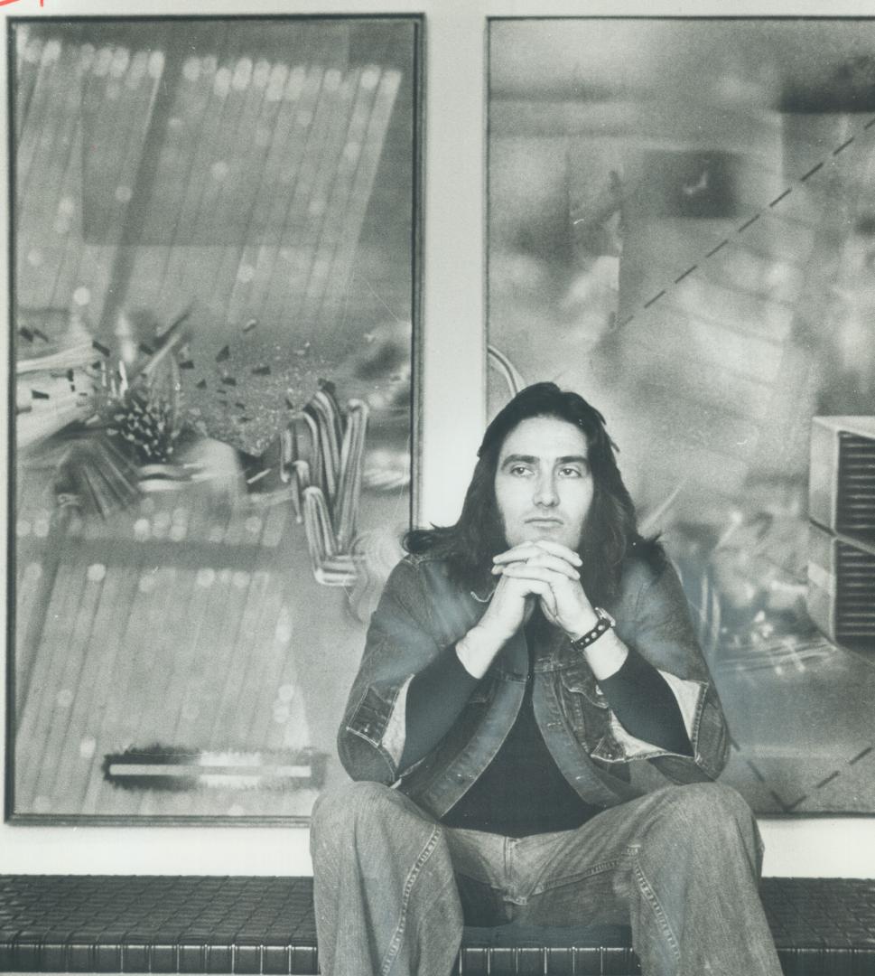 Artist David Wright sits in front of two of his works on exhibition at the Mazelow Gallery, 3463 Yonge St