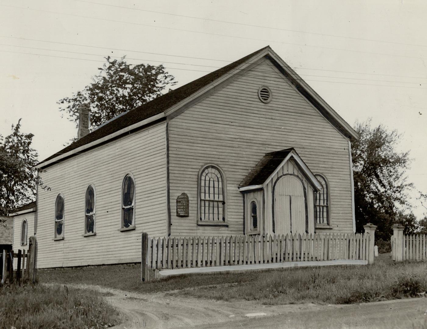 One-story, white, clapboard structure with black sloped roof, arched windows and small covered  ...