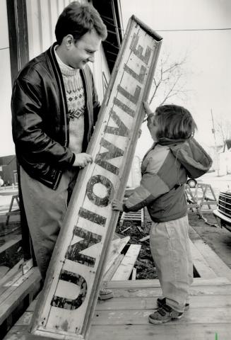 Sign of the times: Architect Stephen LeBlanc and Tova Plashkes, 5, check out the old sign before it's erected on Unionville's restored train station