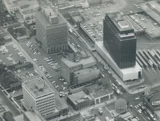 Aerial view showing rooftops of several multilevel buildings, parking lots, and roads.