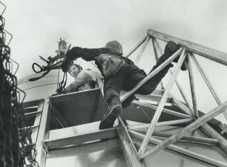 Ironworkers climbing around the weather shield with top of antenna up