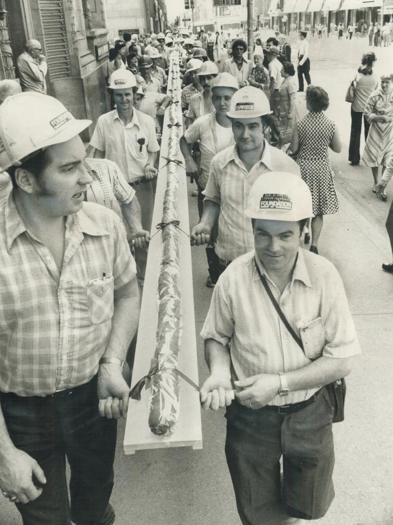 Forty construction workers today carry a 102-foot-long submarine sanwich from Eaton's Queen St