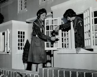 Tea time guidance. Girl Guide Carol Sissons gets cup of imaginary tea from Sue Parks in exact replica of playhouse presented to Queen Elizabeth when s(...)