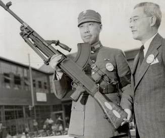 The gun was entrusted to Maj.-Gen. S. M. Chu, military attache to the Chinese embassy in Washington. Gen. Chu. holding the gun, is shown with Dr. Liu (...)