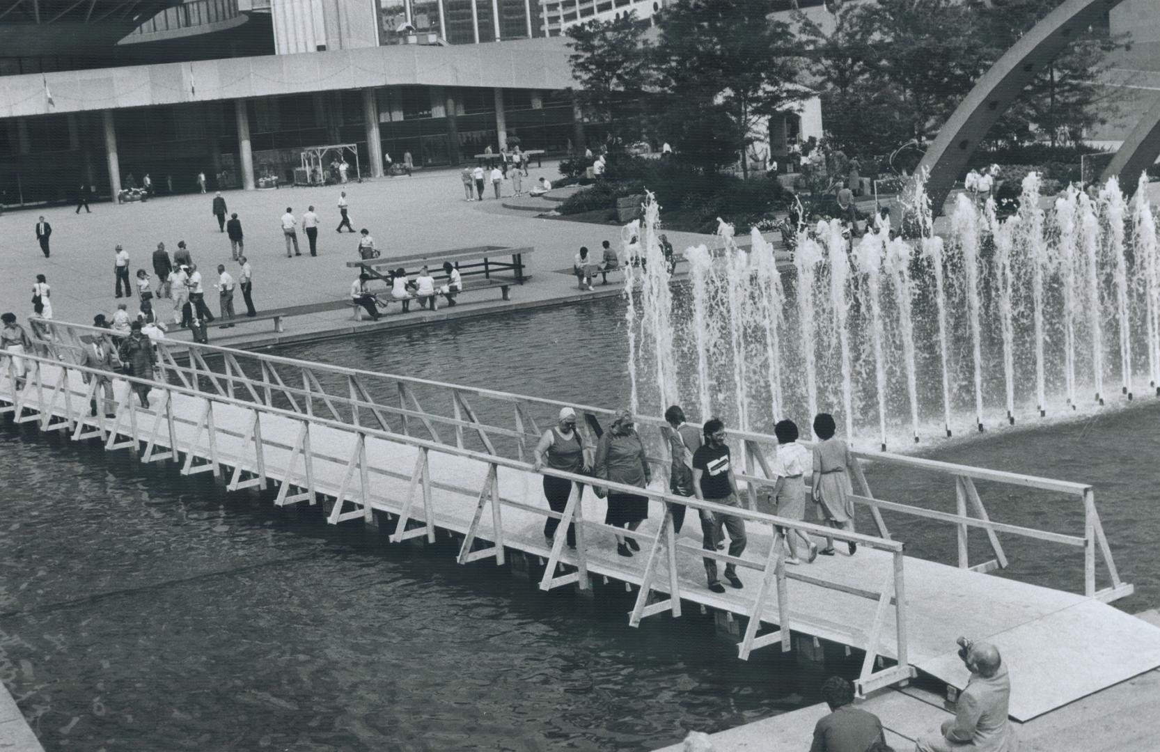 A bridge over bubbled waters, This temporary wooden bridge over the Toronto City Hall reflecting pool is the latest addition to Nathan Phillips Square