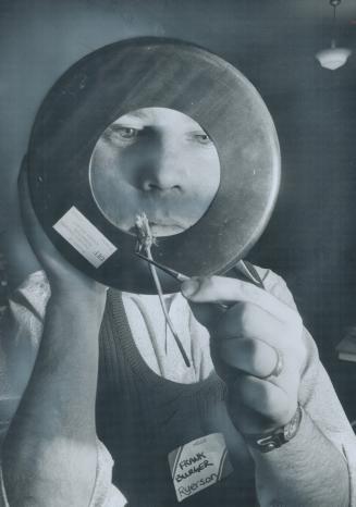 An exaggerated view of a small flower is taken by Frank Burger, of Ryerson Polytechnical Institute, as he peers through an oversized magnifying glass (...)