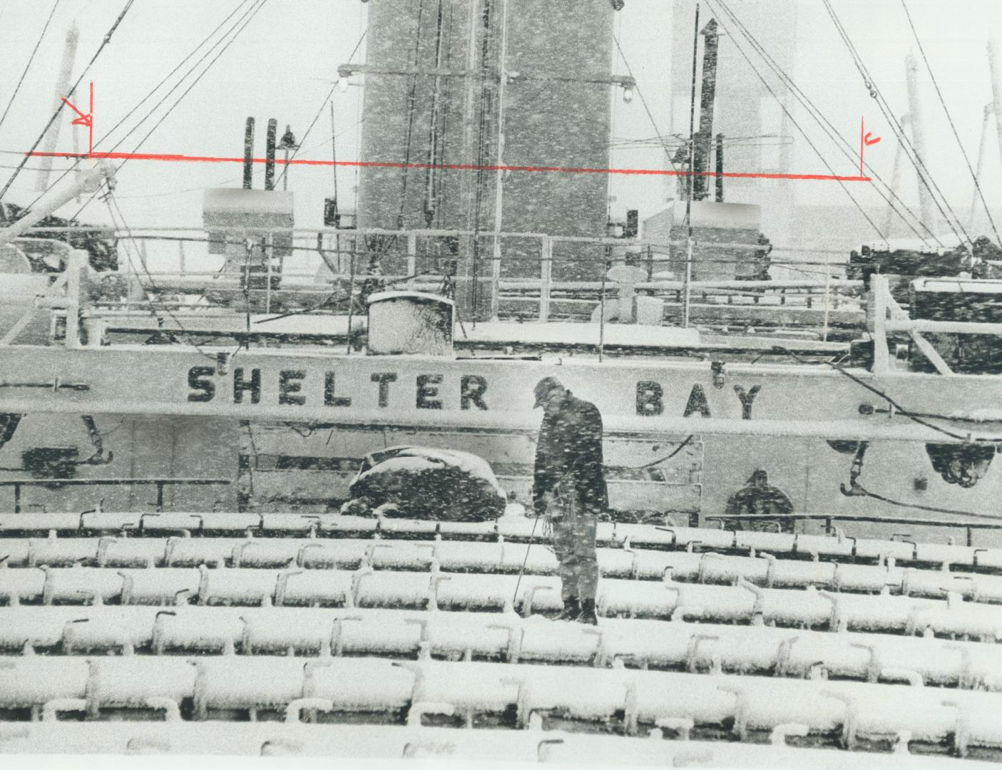 In driving snow, Irvin Golem walks deck of the lake freighter Shelter Bay, sounding her ballast tanks for water with a rope and measuring stick. The v(...)