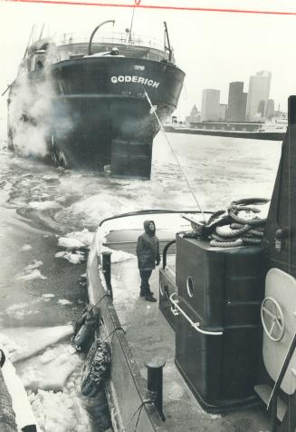 Image shows a tugboat breaking ice for a ship.